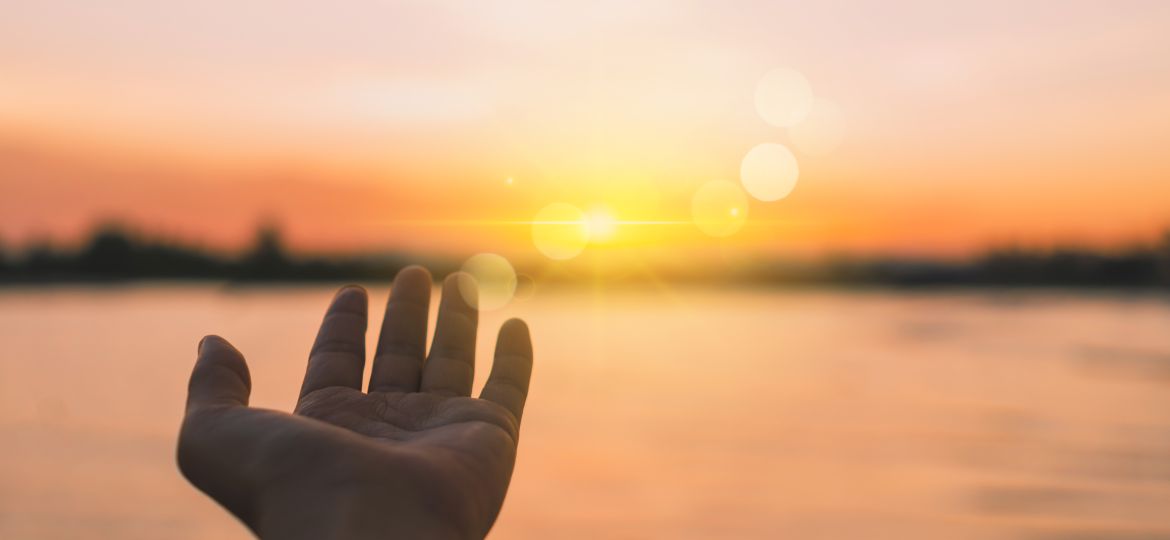 Woman hands reach out to the sky like praying in front of sky.