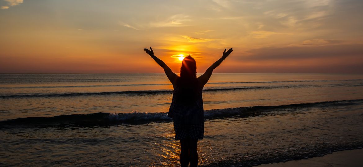 Silhouettes  of Woman raise hands up to the sunrise sky at the b
